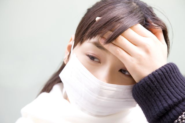 発熱でおでこを押さえる女性